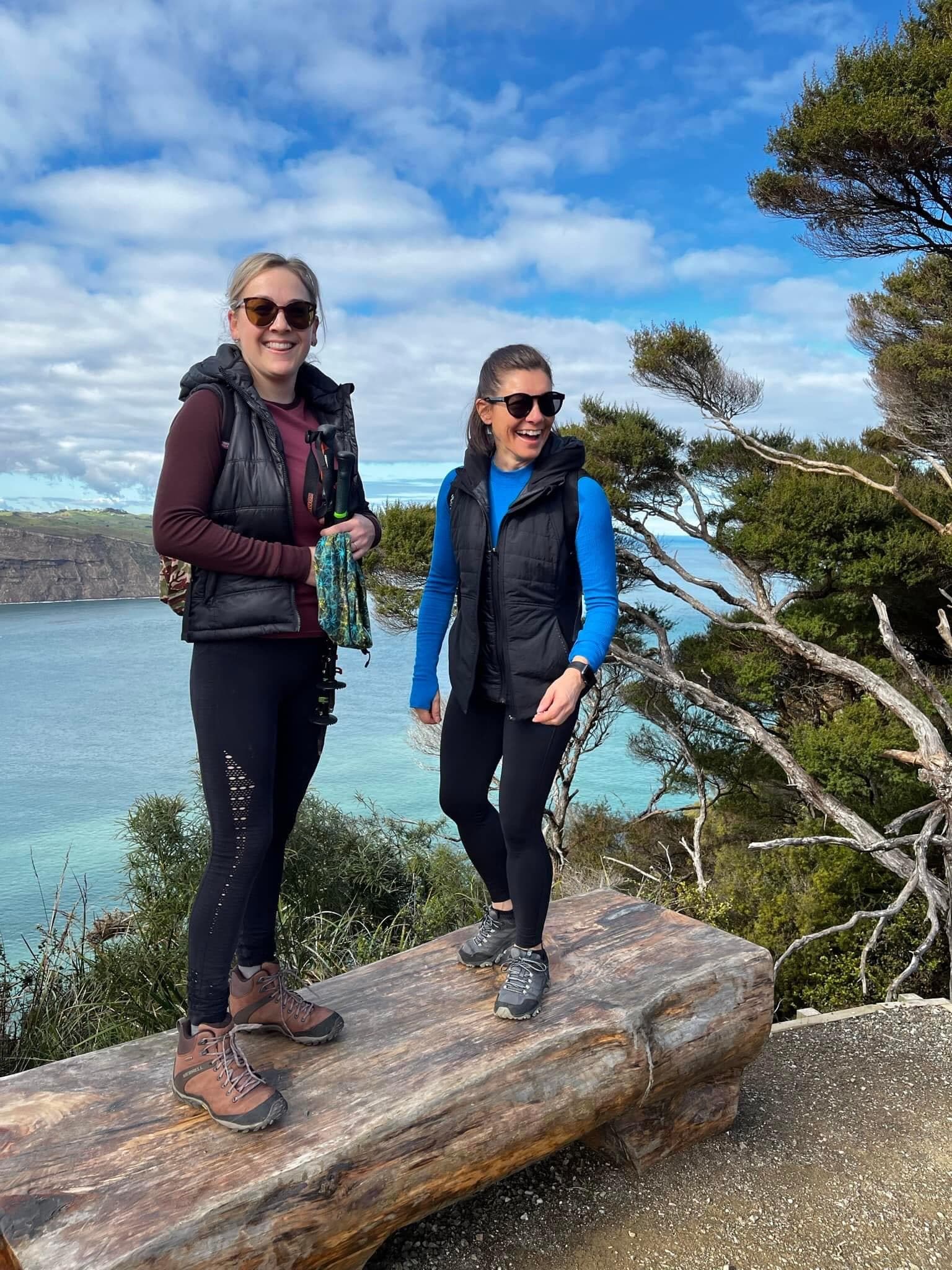 Tash Fernandez hiking with a companion overlooking a coastal bay.